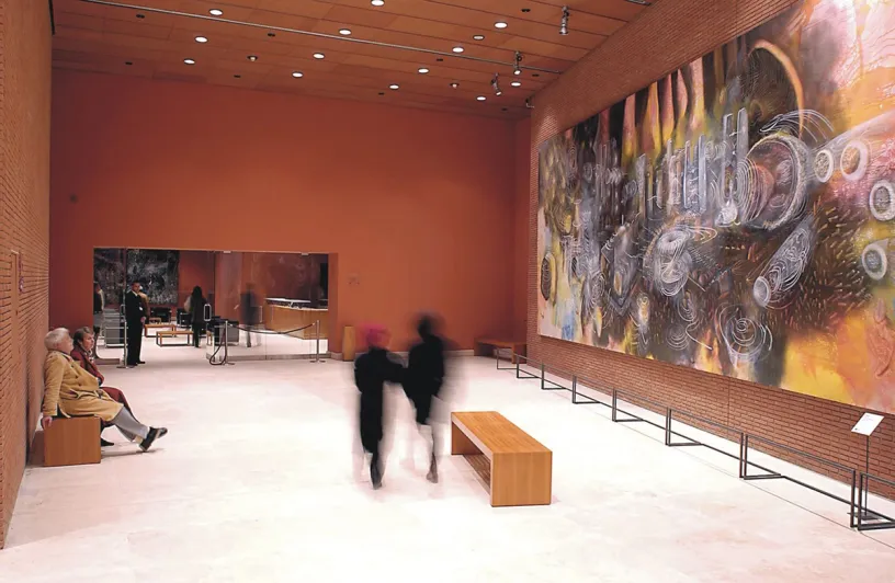 A group of people are walking through a museum with a large painting on the wall
