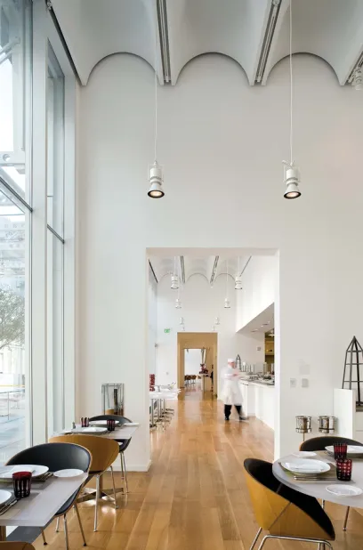 A restaurant with tables and chairs and a chef in the background