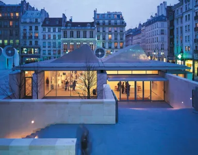 a group of people are walking in front of a building in a city at night .