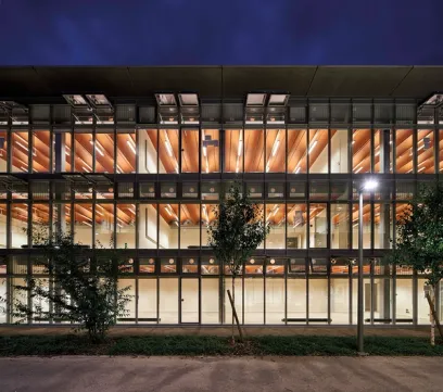 A large building with a lot of windows and trees in front of it at night