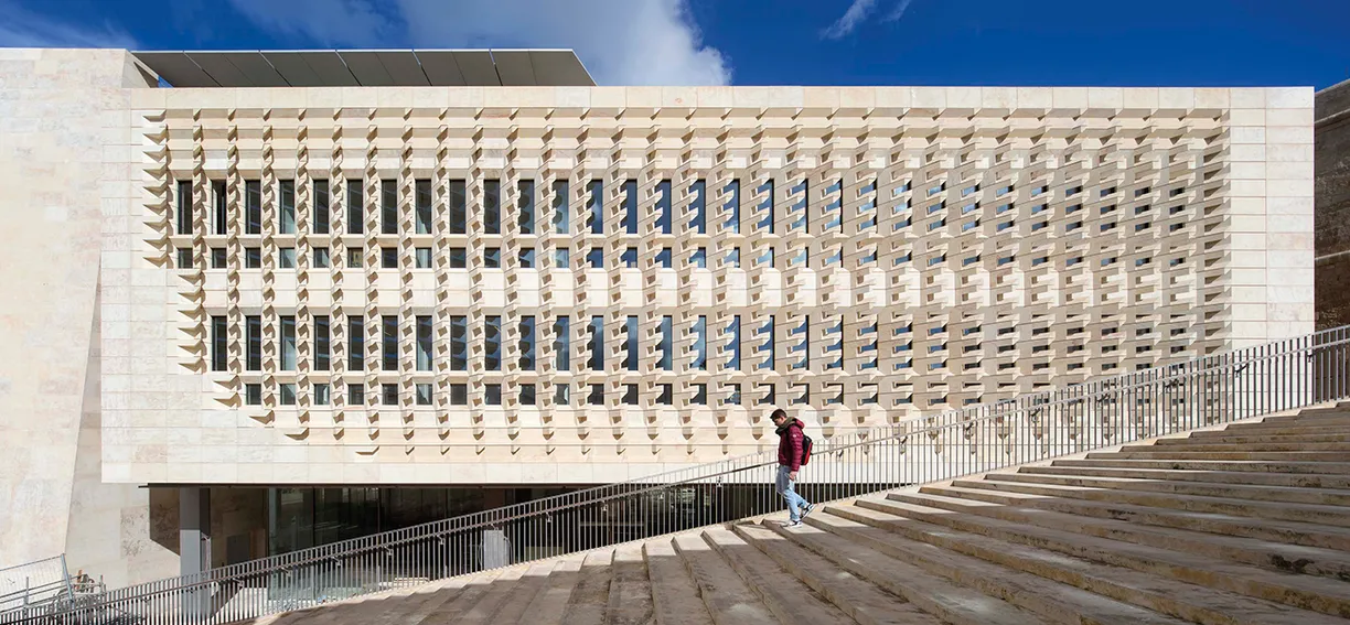 A man is walking down a set of stairs in front of a large building 