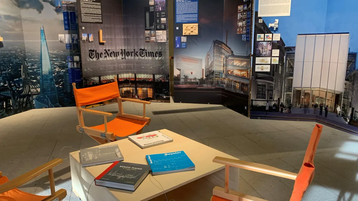 a room with chairs , a table , and a display of the new york times .