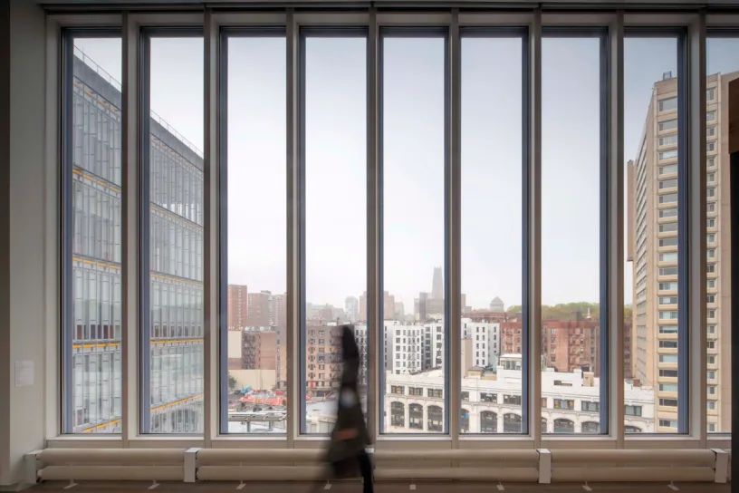 a woman is walking in front of a large window with a view of a city .