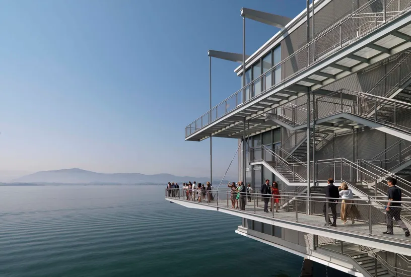 A group of people are standing on a balcony overlooking a body of water