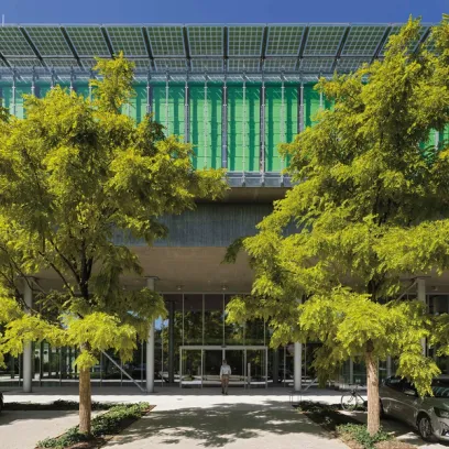 A man is walking in front of a building with trees in front of it