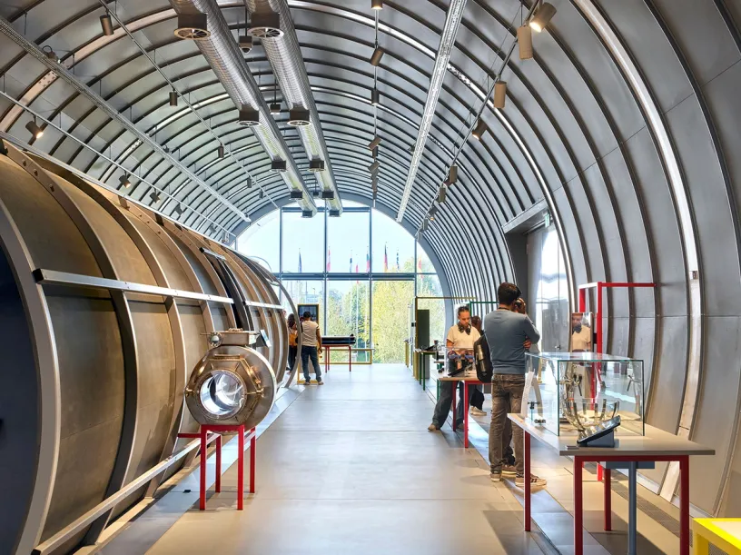 A group of people are standing in a large room in a building