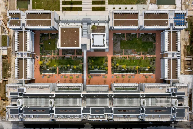 An aerial view of a large building with a lot of windows and trees on the roof
