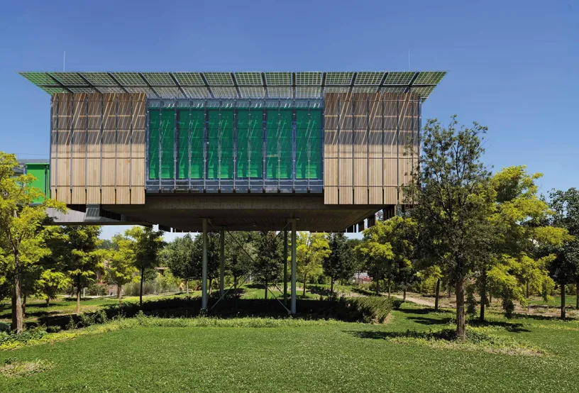 A large green building is sitting on top of a lush green field
