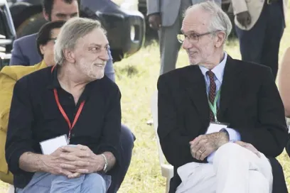 Two men are sitting in the grass talking to each other