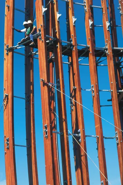two men are working on a wooden structure against a blue sky