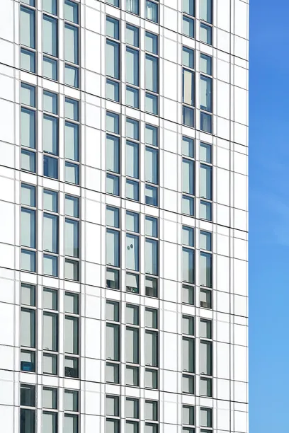 Modern white building facade with a grid of windows against a blue sky.