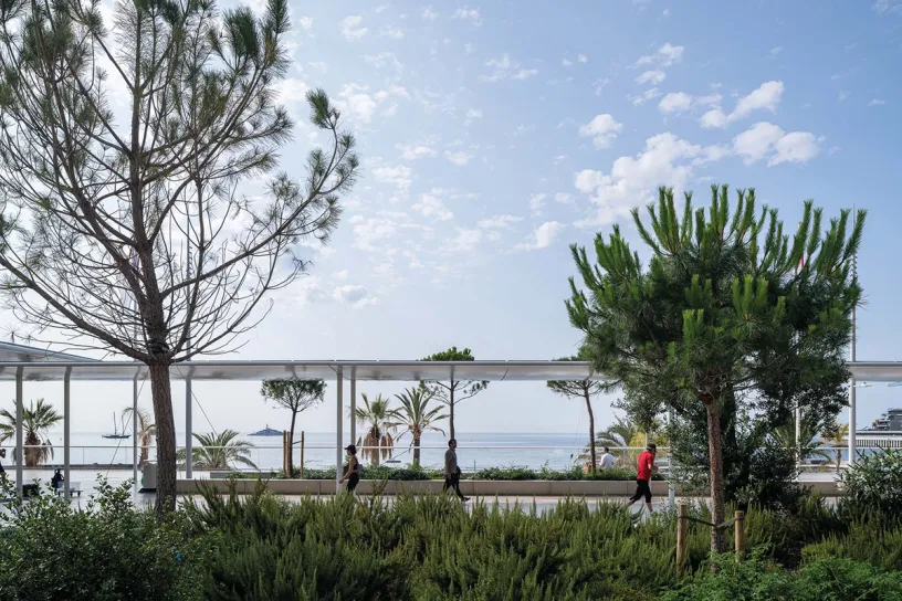A group of people are walking under a canopy overlooking the ocean