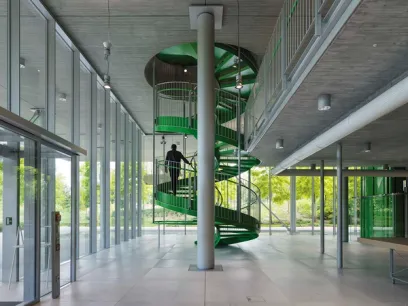 A man is walking up a green spiral staircase in a building