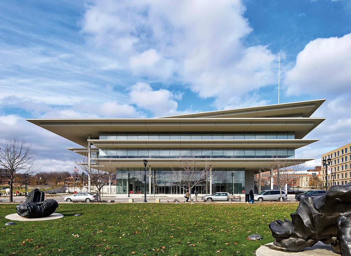 A large building with a lot of windows is sitting on top of a lush green field