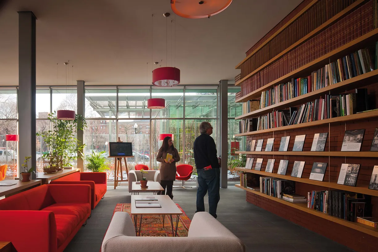 A man and a woman are standing in a library looking at books
