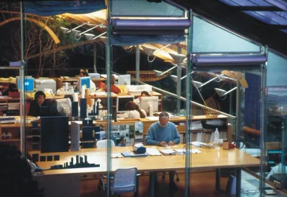 A man is sitting at a table in a glass office