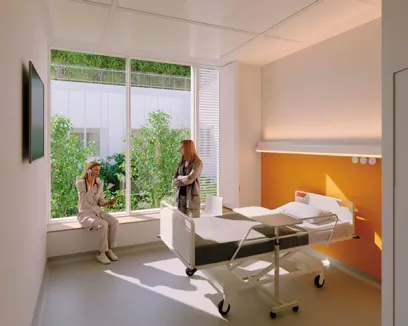A woman is sitting on a window sill next to a hospital bed talking on a cell phone