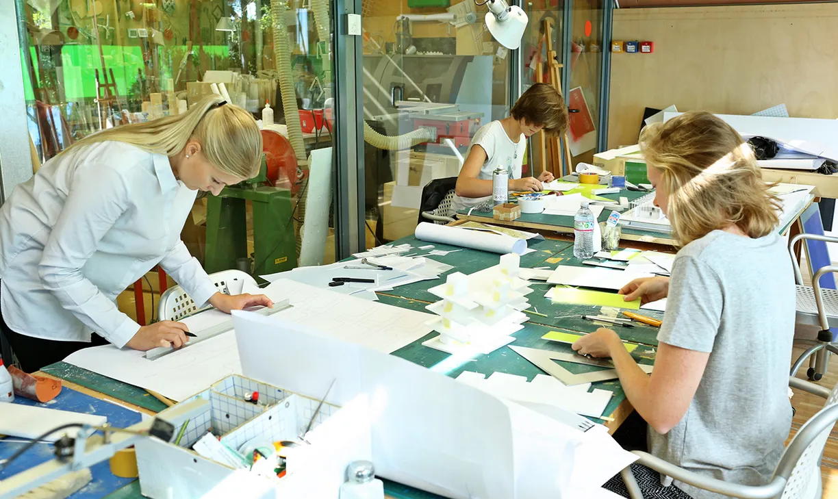 A group of people are sitting at a table working on a project