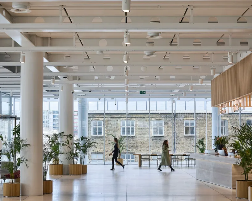 Two women are walking through a large lobby in a building