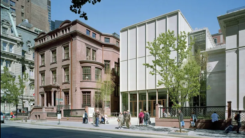 a group of people are standing on the sidewalk in front of a building .