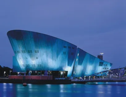 A large blue building is sitting on top of a body of water
