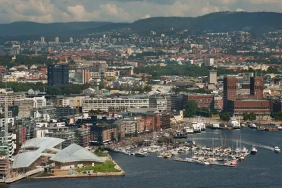 An aerial view of a city with boats docked in the water and mountains in the background
