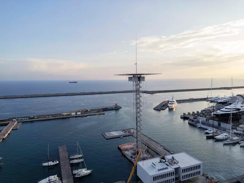 An aerial view of a marina with boats docked and a tower in the middle of the water
