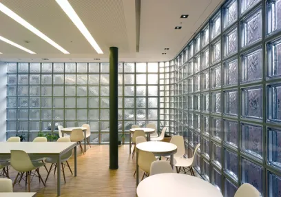 A dining room with tables and chairs in front of a glass wall