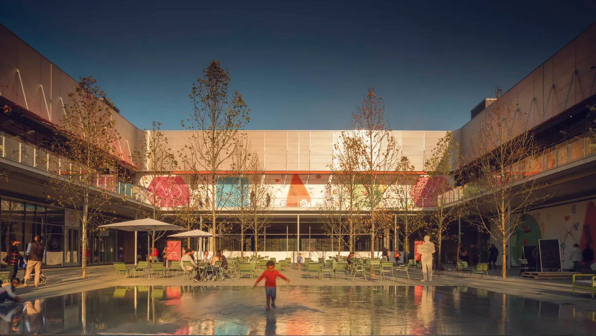 a little boy is playing in a fountain in a courtyard in front of a building .