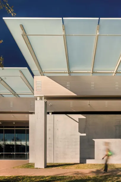 A person walking under a glass canopy in front of a building 
