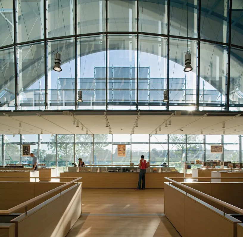 A woman is standing at a counter in a large building with a lot of windows