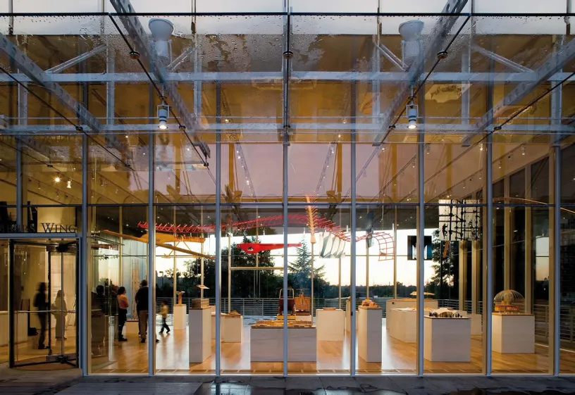 A group of people are standing in front of a glass building