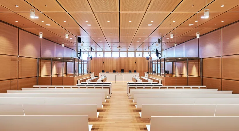 A large courtroom with rows of benches and a wooden ceiling