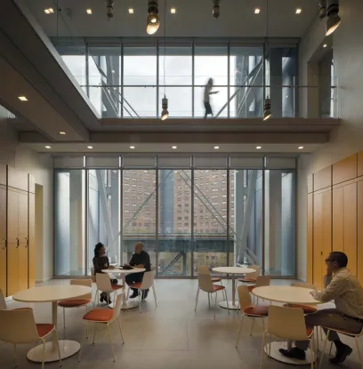 a group of people are sitting at tables in a room with lots of windows