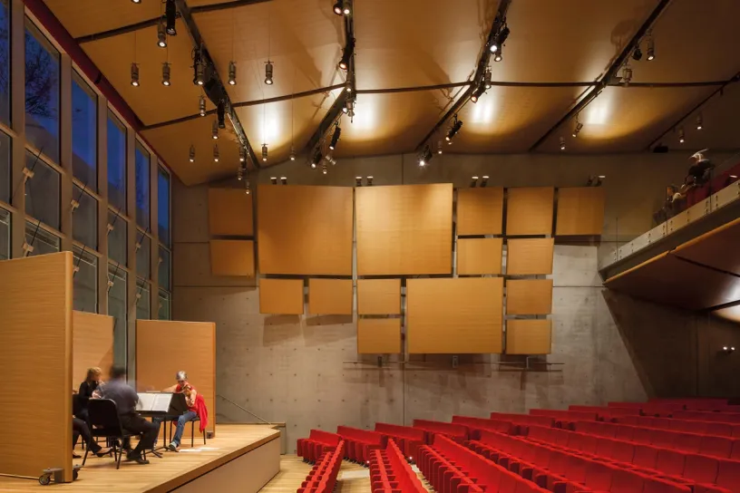A group of people are playing instruments in a large auditorium
