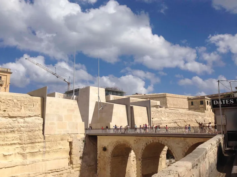 a group of people are walking across a bridge in front of a large building