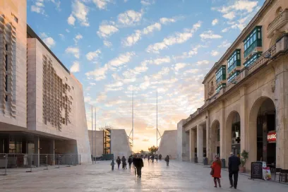 A group of people are walking down a street in front of a building at sunset
