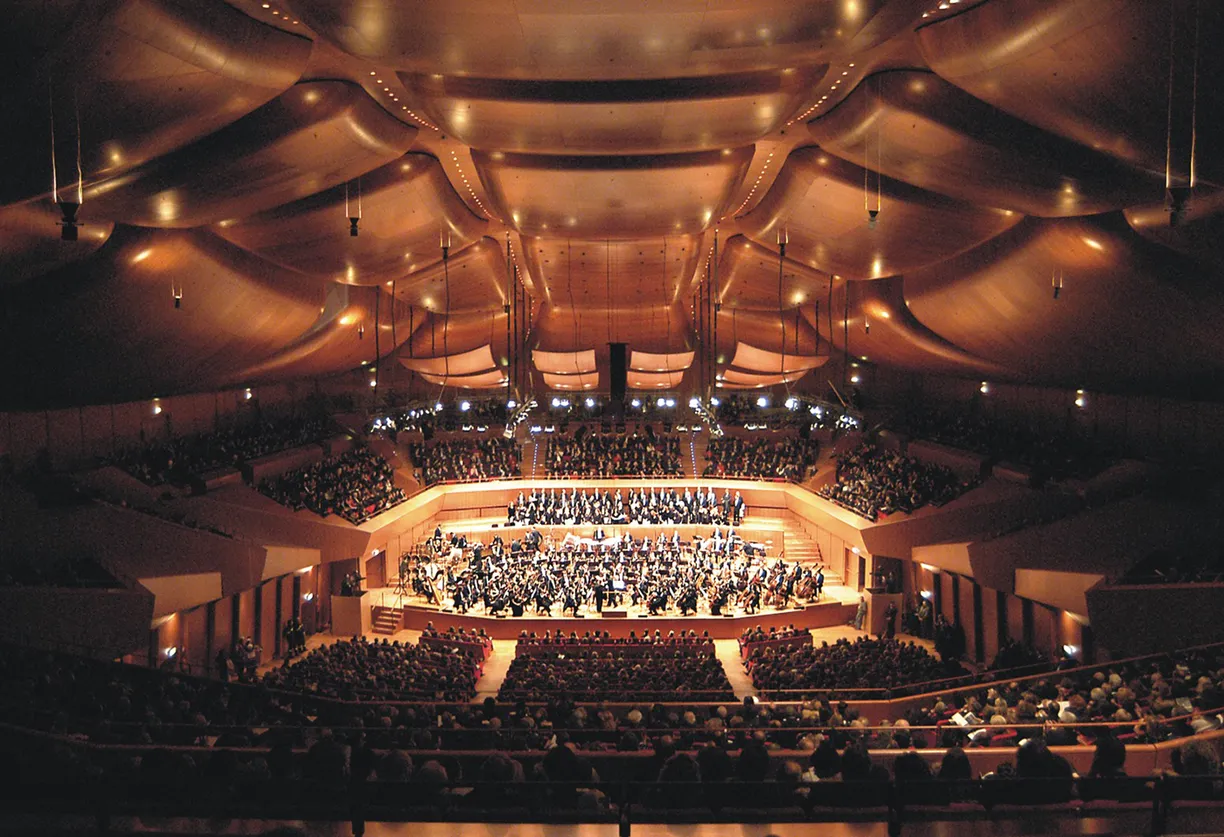 A large auditorium filled with people watching an orchestra perform