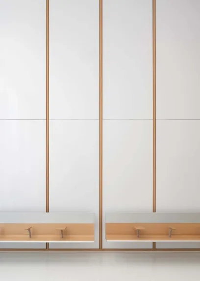A row of white cabinets with wooden trim and drawers against a white wall