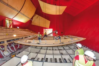 a group of construction workers are working on a large wooden structure in a building .