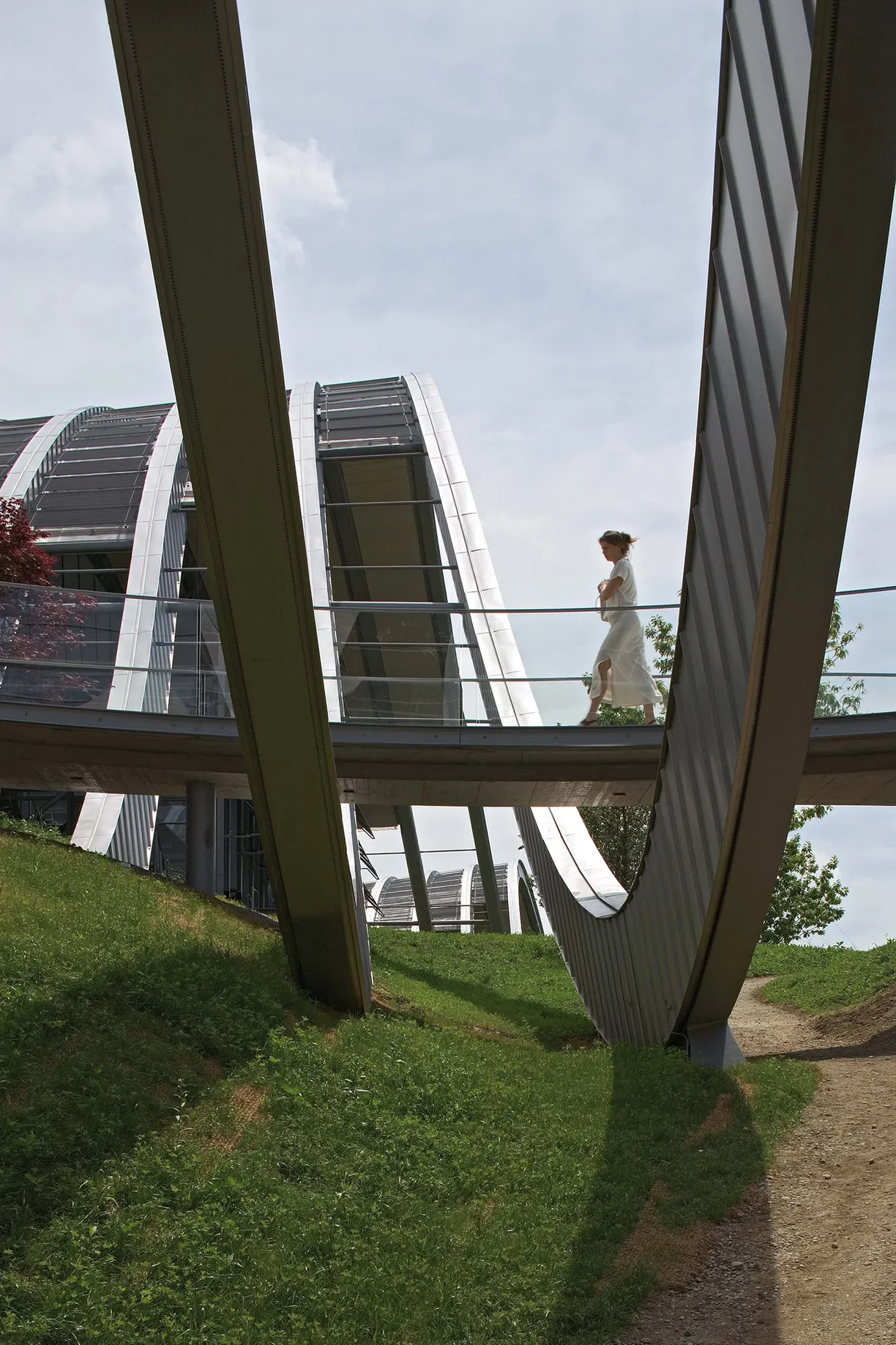 A woman in a white dress walks across a bridge
