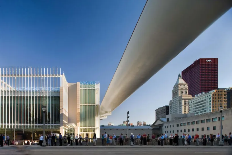A group of people are standing on a bridge in front of a building