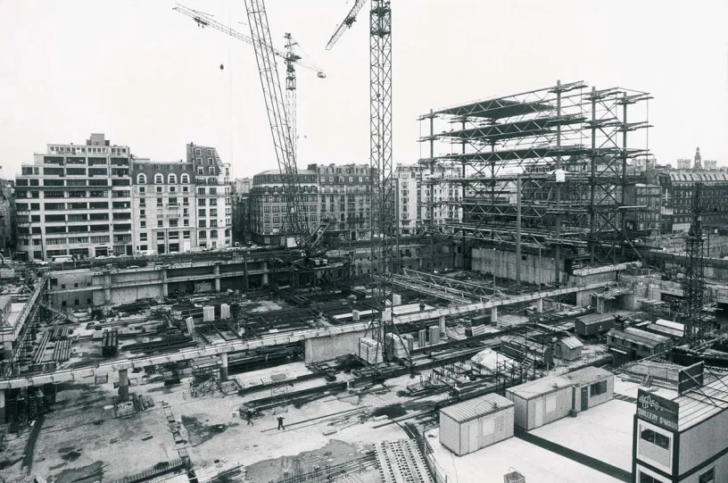 A large building is being built in a city in a black and white photo