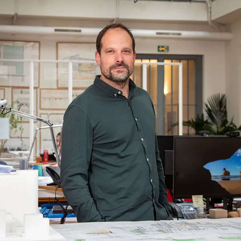 A man in a green shirt stands with his hands in his pockets
