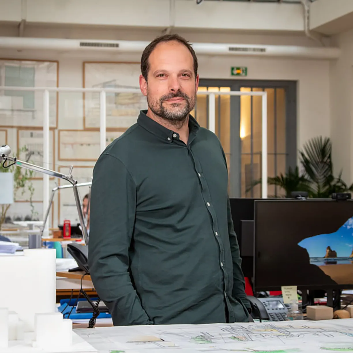 A man in a green shirt stands with his hands in his pockets