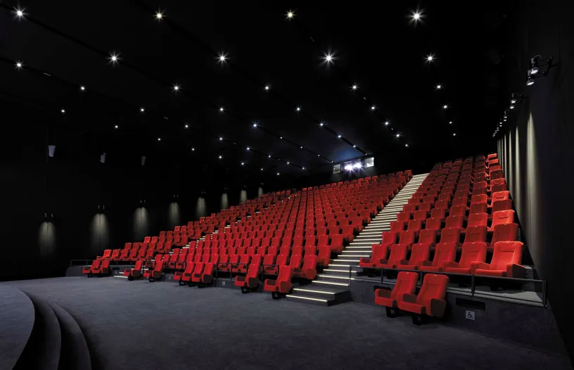 A large auditorium filled with red seats and stairs