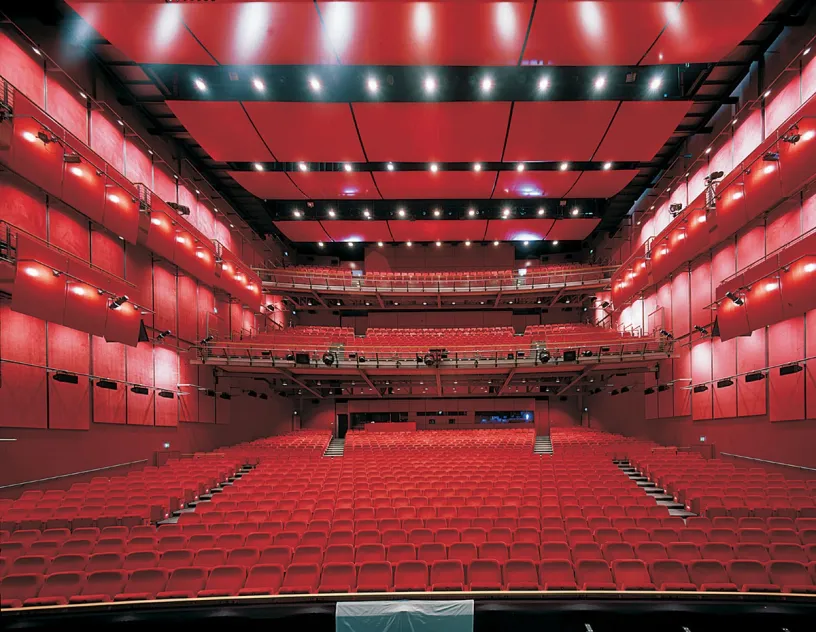 A large empty auditorium with red seats and a stage