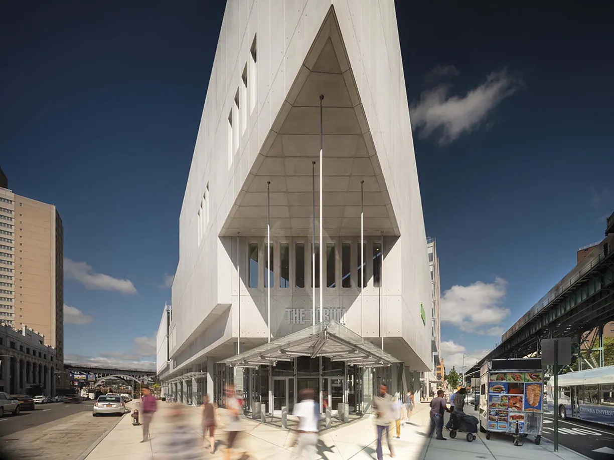 A group of people are walking down a sidewalk in front of a large white building