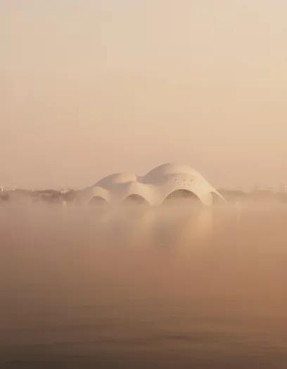a large white building is surrounded by fog over a body of water