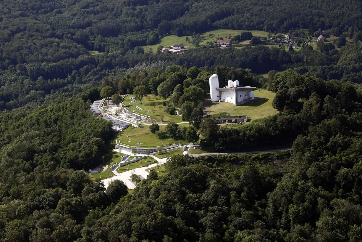 An aerial view of a building on top of a hill surrounded by trees